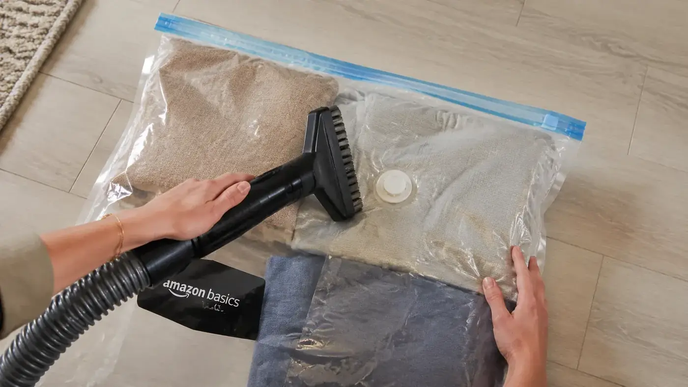 Vacuum hose nozzle held next to a vacuum bag valve showing the size mismatch between a wide brush head and the small valve port